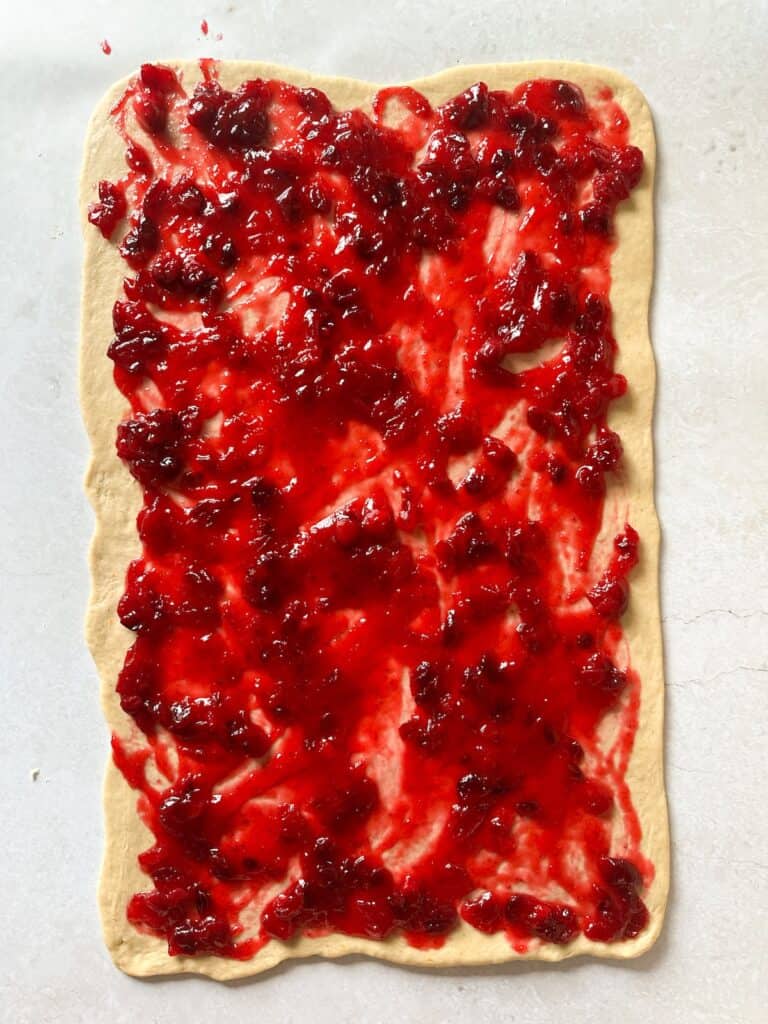 cranberry sauce spread over rolled out dough.