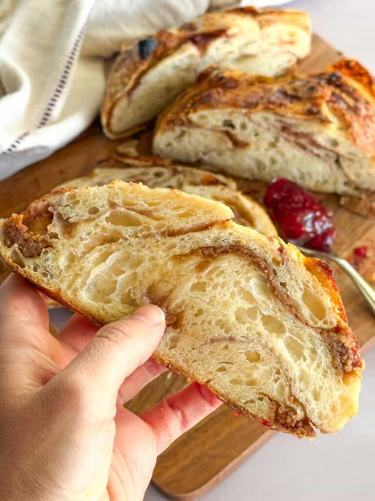 hand holding slice of peanut butter jelly sourdough bread.