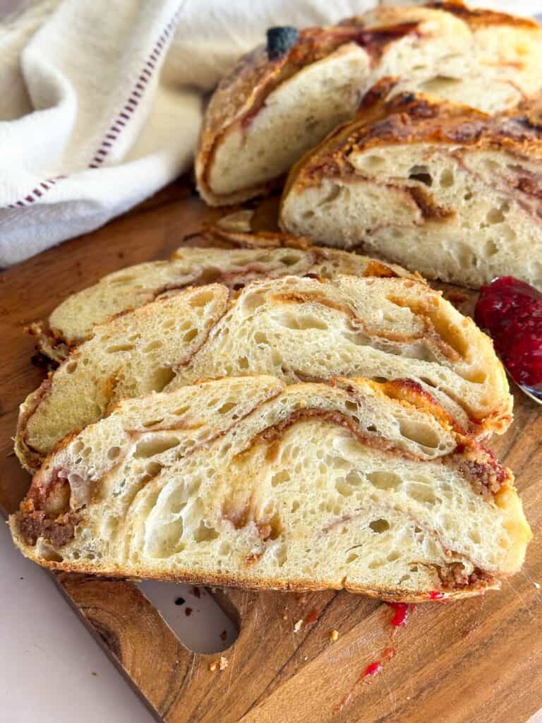 Slices of peanut butter and jelly sourdough bread on a wooden cutting board.