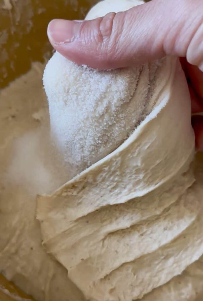 a hand mixing salt into sourdough dough after fermentolyse.