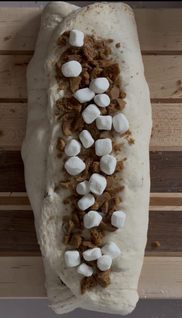 s'mores sourdough bread dough topped with remaining graham crackers and marshmallows before being rolled for final shaping