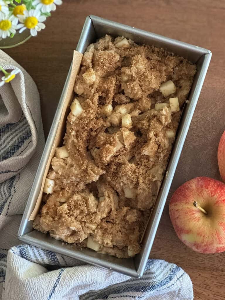 sourdough discard apple bread batter in a loaf pan after it has been swirled with a knife.