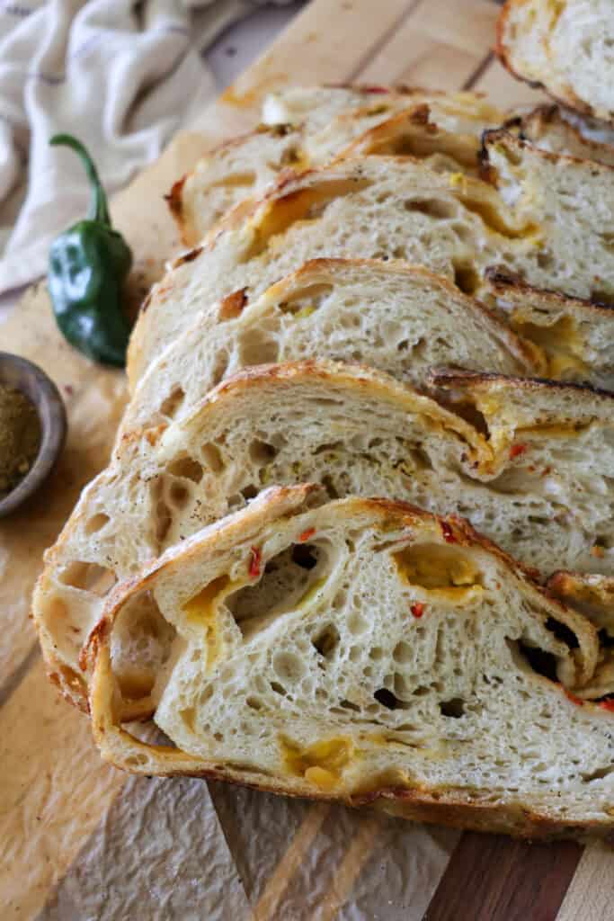 sourdough green chile cheddar bread sliced on a cutting board.