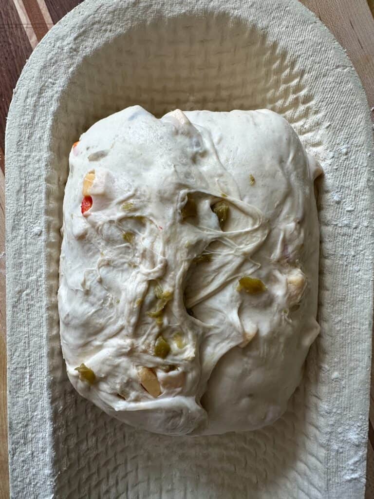 sourdough green chile loaf shaped in banneton.
